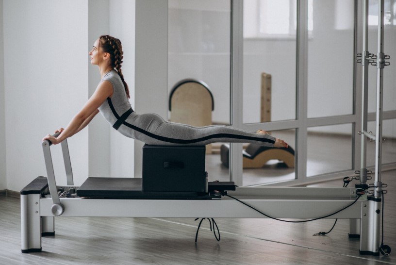 Woman practicing pilates on a reformer.